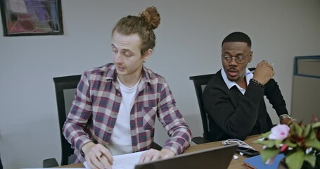 Canvas Print - Mixed-race professionals collaborate during a business meeting in an office environment. They work together, sharing ideas and insights, fostering an atmosphere of teamwork and innovation.