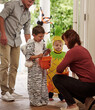 © peopleimages.com - Halloween, children and parent at house for candy, costumes and trick or treat in neighborhood together. Kids, dad and woman giving sweets for dress up in home, fun and development in October