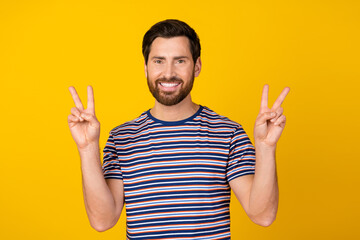 Sticker - Photo of optimistic handsome man with stylish beard dressed striped t-shirt showing v-sign symbol isolated on yellow color background