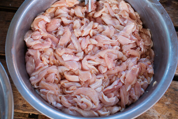 Close-up of chicken meat cut into pieces and placed in a stainless steel container.