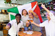 © JackF - Diverse group celebrating with Italian flag at a pub with beer
