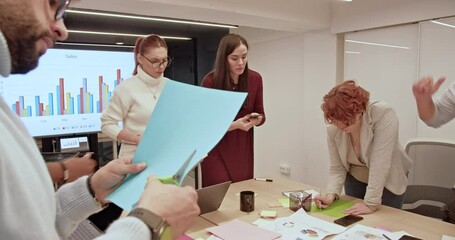 Canvas Print - A multiethnic group of company employees enthusiastically sharing ideas and analyzing data for project planning during a business meeting.