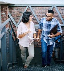 Canvas Print - Walking, discussion and business people with creative ideas, project proposal and laptop in office. Designer, man and woman at digital agency with paperwork, conversation and brainstorming on stairs.