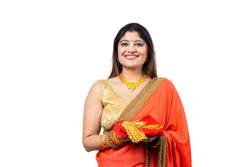 Young beautiful Indian woman wearing red saree holding gold jewelry ornaments in hand standing against white background, Concept of Gold Loan.