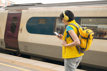 Female in headphones checking train timetable on mobile