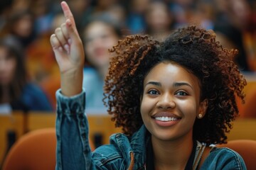 Smiling Black female student raising her hand in a college classroom, wearing a denim jacket.