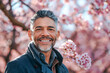 © MVProductions - Portrait of an handsome South American hispanic man posing in front of a blooming cherry tree , close-up view of a cheerful beautiful latino white middle aged male in an outdoor park