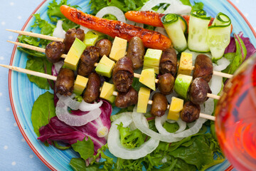 Wall Mural - Delicious fried shish kebab from chicken hearts served with avocado and fresh lettuce at plate