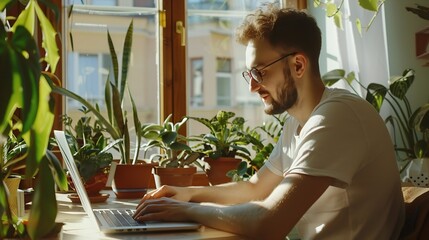 Satisfied handsome millennial man typing on laptop computer while sitting at table near window with potted plants communicating online writing emails distantly working or studying on c : Generative AI