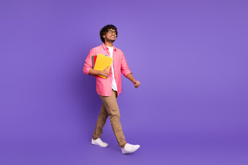 Canvas Print - Full body portrait of nice young man hold book walk empty space wear shirt isolated on purple color background