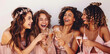 © Sourav Mittal - 4 beautiful smiling women in pink dresses laughing holding champagne glasses, one woman has long curly hair with braids wearing a crown on white background, photo shot from the side in the style of st