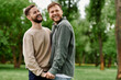 © Bliss - Two bearded men, an LGBTQ couple, laugh together in a green park on a sunny day.