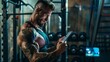 © Emiliia - A muscular man with tattoos checks his workout plan on a tablet in a gym.