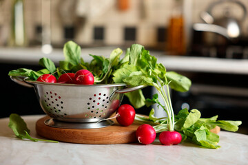 Metal colander with fresh radishes on white table