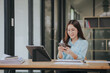 © Witoon - Beautiful Asian woman smiling happily working in modern office with documents, tablets and mobile phones on the table