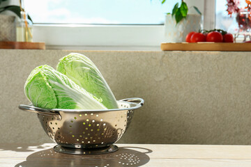 Wall Mural - Fresh Chinese cabbages in colander on light wooden table indoors. Space for text
