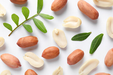Fresh peanuts and green leaves on white background, flat lay