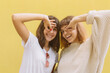 © anatoliycherkas - Two stylish school friends girl joking and make faces grimace with hands on the yellow background