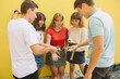 © anatoliycherkas - Group teenagers playing rock paper scissors game over yellow background