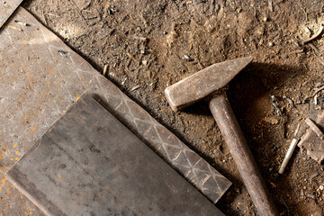 A metal hammer used for forging iron stands on an iron floor in a metal workshop in Turkey