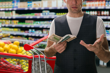 Wall Mural - Upset young man doesn't have enough money to shop at grocery store. Financial transaction: Hands exchange cash dollars for supermarket purchases