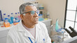 © Krakenimages.com - Mature, grey-haired man in white lab coat pondering in a well-equipped laboratory setting