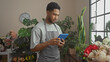 © Krakenimages.com - African american man using tablet in flower shop surrounded by greenery and floral arrangements.