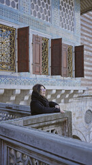 Wall Mural - A contemplative woman leans on an ornate balcony of topkapi palace, showcasing islamic architecture in istanbul.