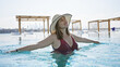 © Krakenimages.com - Young brunette woman enjoys luxury pool at a beachfront with skyline in background
