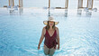 © Krakenimages.com - Smiling woman wearing a sunhat and swimsuit enjoys a sunny day at a luxury poolside