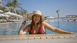 © Krakenimages.com - A smiling woman wearing a sunhat relaxes in a luxurious pool at a sunny resort, embodying leisure and happiness.