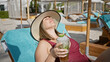 © Krakenimages.com - A relaxed woman enjoying a cocktail at a luxurious poolside beach club.