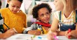 © peopleimages.com - Happy children, drawing and paper with class in kindergarten for fun activity or coloring in classroom. Group of young elementary kids sketching colorful poster or sign for learning and development