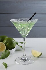 Wall Mural - Delicious Margarita cocktail with ice cubes in glass and lime on white table