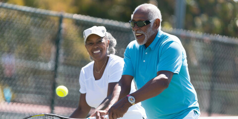 Wall Mural - an African American retired couple playing tennis at a community center