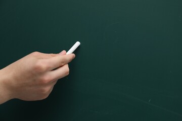Wall Mural - Teacher writing with chalk on green chalkboard, closeup. Space for text
