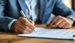 © Arrseman - Close-up of a businessman in a suit signing a document on a wooden desk, signifying professionalism and contracts