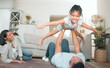 © peopleimages.com - Relax, parents and kid on floor with airplane for support, bonding and portrait in living room. Happy family, playing and child development in lounge with fun, trust and games in home for happiness