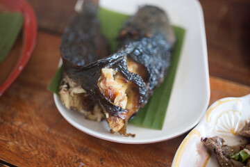 Wall Mural - Catfish roasted on banana leaf. Street food in Thailand.