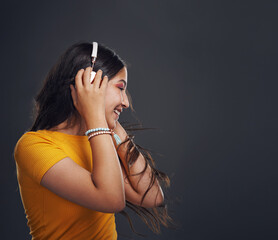 Girl, headphones and music in studio for dancing, profile and streaming online on gray background. Female person, mockup space and rock for audio connection, listening and subscription for podcast