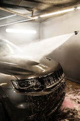 Wall Mural - Washing the foam from the surface of the vehicle. Cleaning the car body with a high pressure water jet at a self serve car wash.