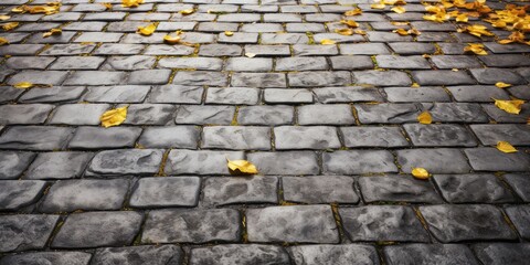 Wall Mural - Autumn Background with Yellow Leaves on Old Gray Pavement or Granite Cobblestone Road top View