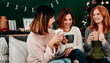 © HockleyMedia24/peopleimages.com - Coffee, women and friends for Christmas celebration and talking together for vacation reunion on sofa. Female people, group and smile with hot chocolate drink for happy conversation and festive decor