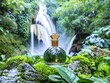 © Peter@studio5 - Product photography, commercial image of essence bottles placed on green trees and moss stones in front of a waterfall, with ornate gold caps.