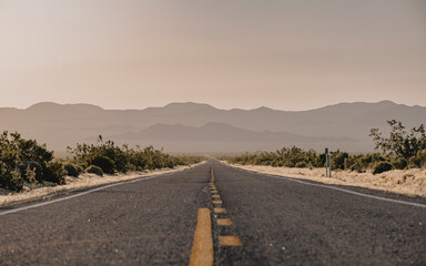 Wall Mural - Long highway in Mojave Desert with sun flare. 