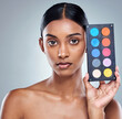 © peopleimages.com - Beauty, makeup palette and woman with portrait in studio for cosmetics, powder or foundation on gray background. Face, skincare and model with cosmetology product, facial glow and eyeshadow