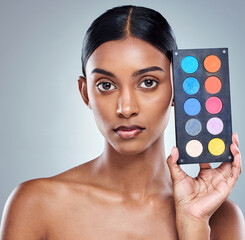 Beauty, makeup palette and woman with portrait in studio for cosmetics, powder or foundation on gray background. Face, skincare and model with cosmetology product, facial glow and eyeshadow