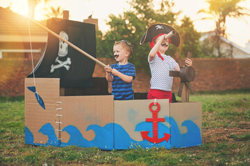 Pirate, boat box and playing with children in backyard for brothers bonding, imagine and creative. Happy, youth and siblings for sailing captain in cardboard ship outdoor for fun, fantasy and games