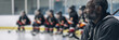 © sommersby - A hockey coach watches intently as his players practice on the ice rink. He is seated in the stands, with a focused expression on his face
