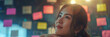 © sommersby - A young woman with long, dark hair looks thoughtfully at a wall covered in brightly colored sticky notes. The lighting is warm and inviting, suggesting a creative and inspiring environment